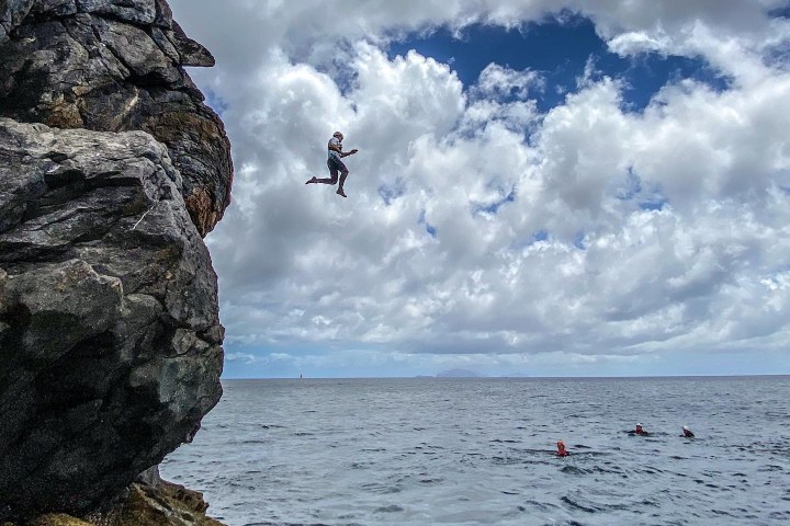 a person sitting on a rock near the ocean